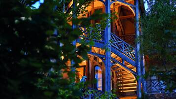 Une structure en forme de tour, faite de bois, avec un escalier en colimaçon, entourée de verdure.