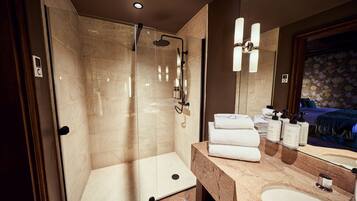 A modern bathroom with a glass-enclosed shower, a marble vanity, and a large mirror.