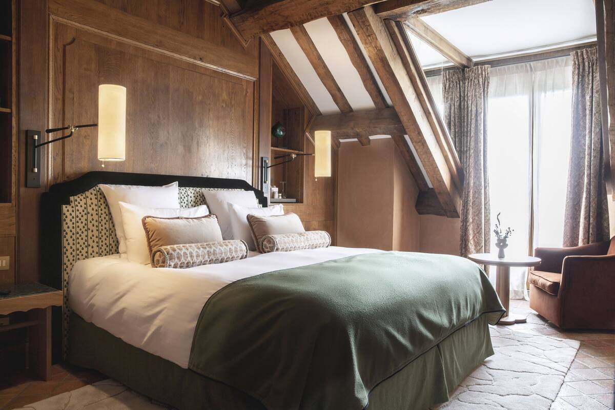 Un dormitorio con una cama grande, paredes de madera, una mesita y una silla.
