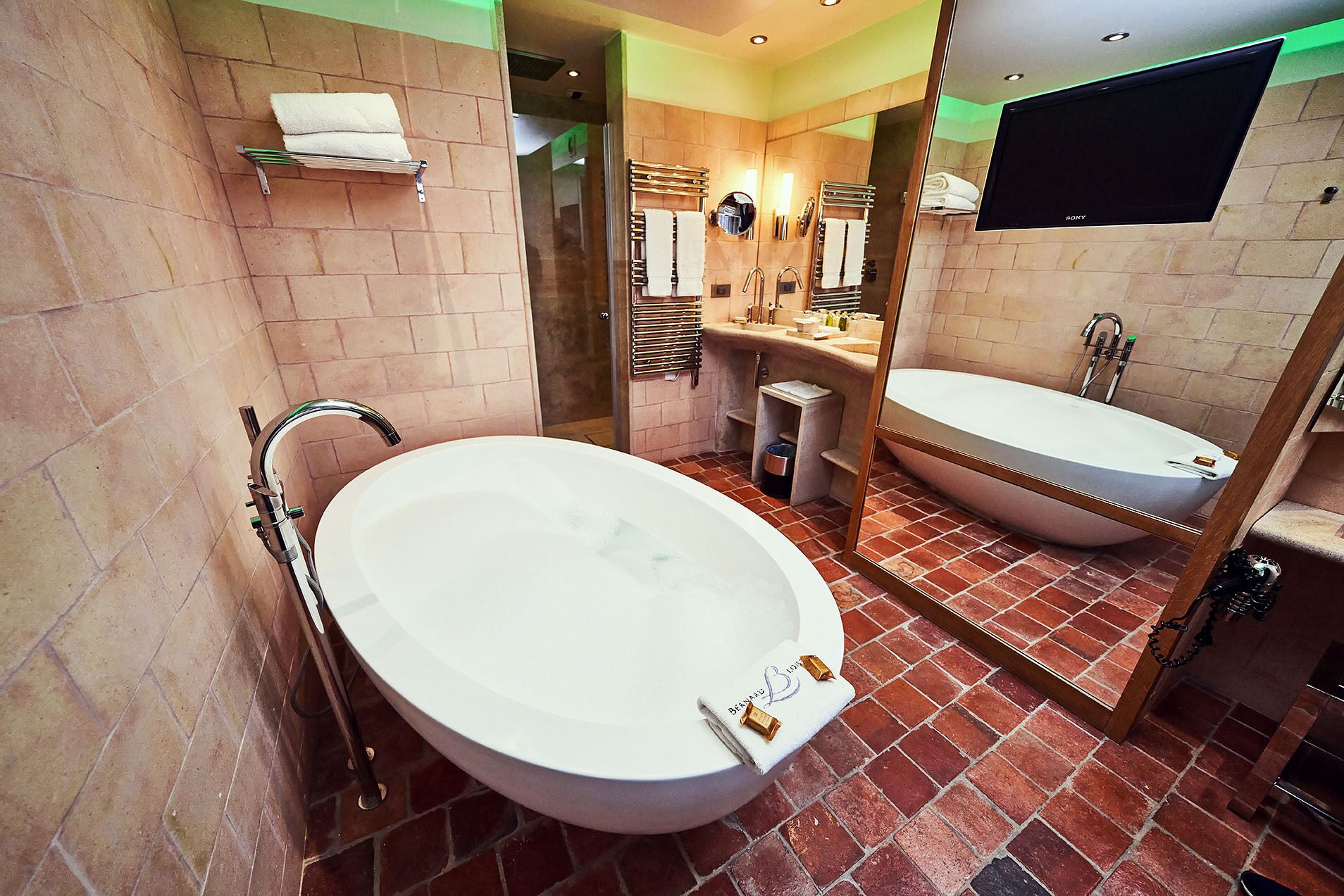 Une salle de bain avec une baignoire sur pieds, un lavabo séparé et un grand miroir.