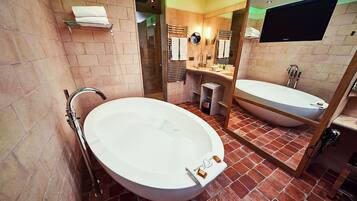 Une salle de bain avec une baignoire sur pieds, un lavabo séparé et un grand miroir.
