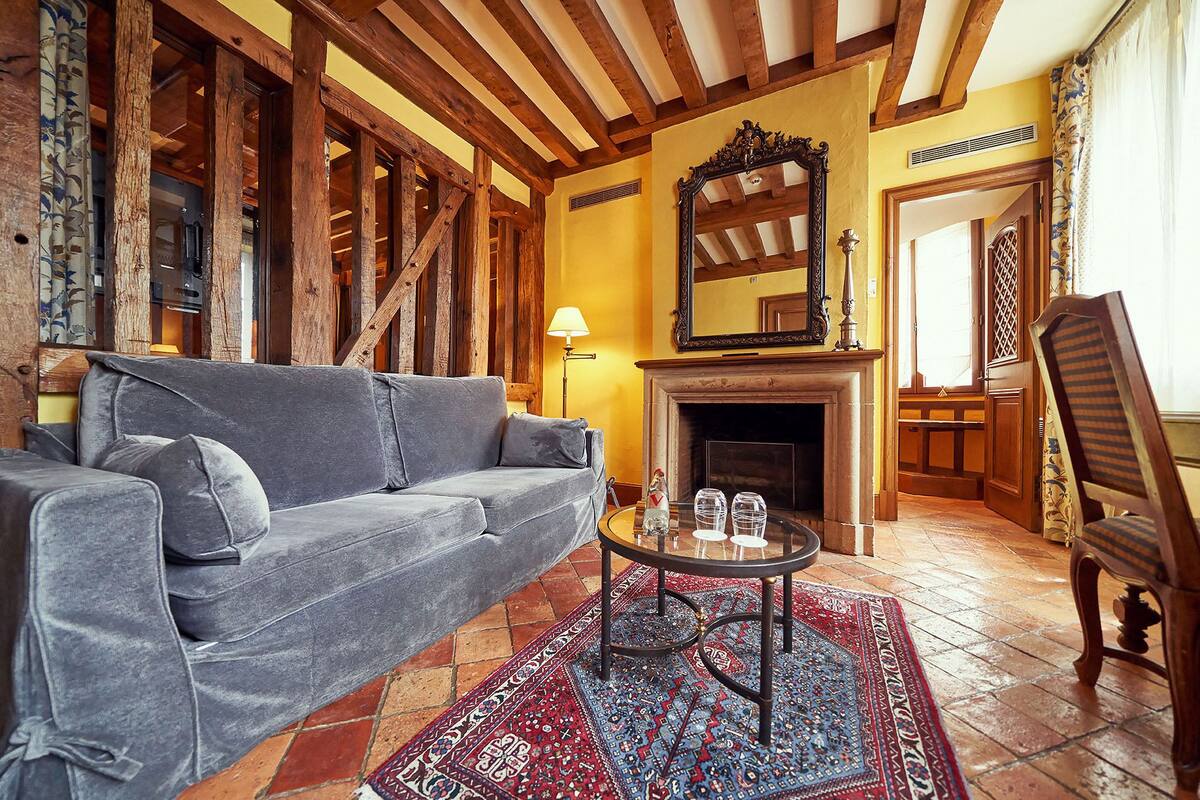 Una sala de estar acogedora con un sofá, una chimenea, una mesa con vasos y una alfombra estampada.