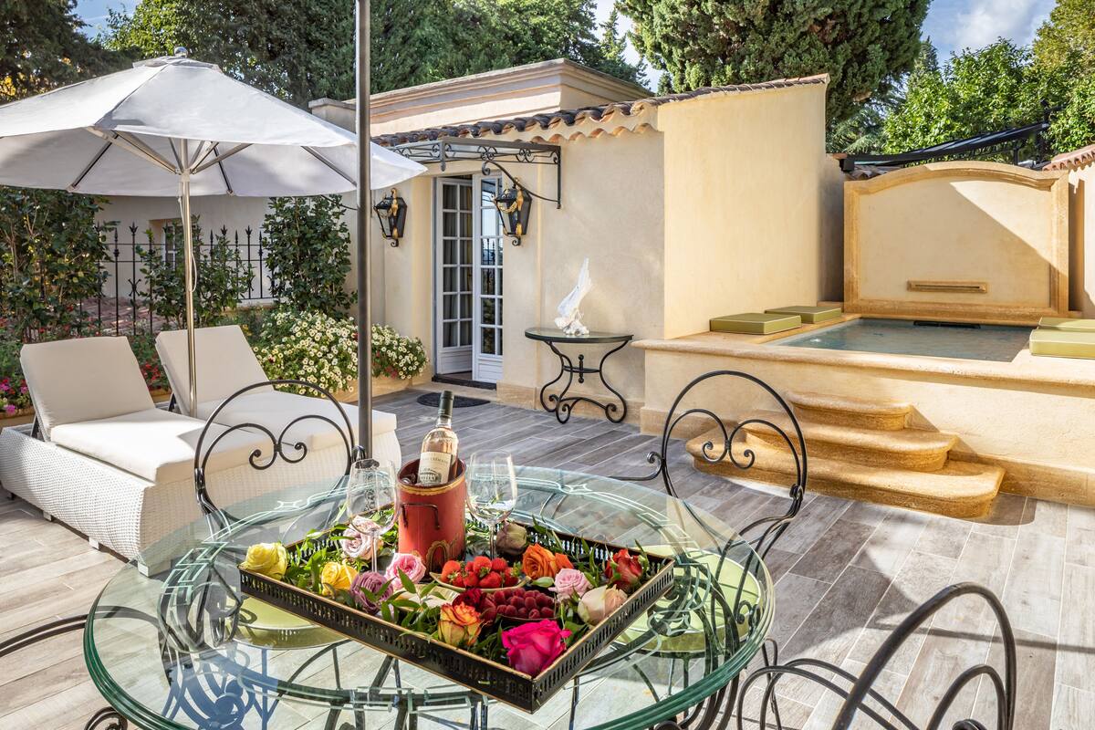 Une table à plateau en verre, avec une bouteille de vin, un verre et une corbeille de fleurs.