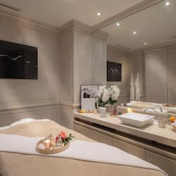 Relax in a serene spa room with a comfortable seating area, vanity, and large mirror.