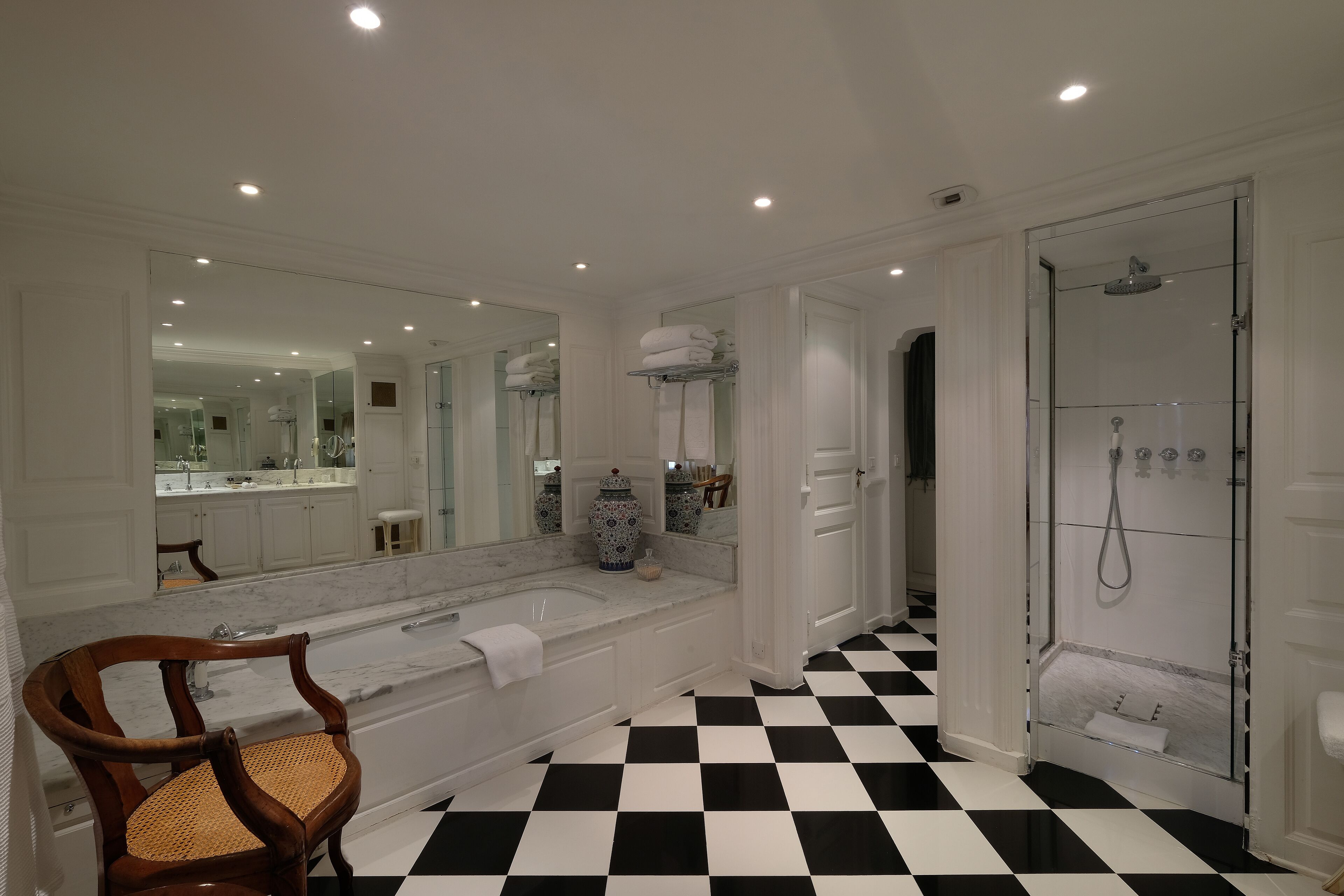 Une salle de bain avec un grand miroir, une baignoire, une douche et un carrelage à motifs à carreaux.