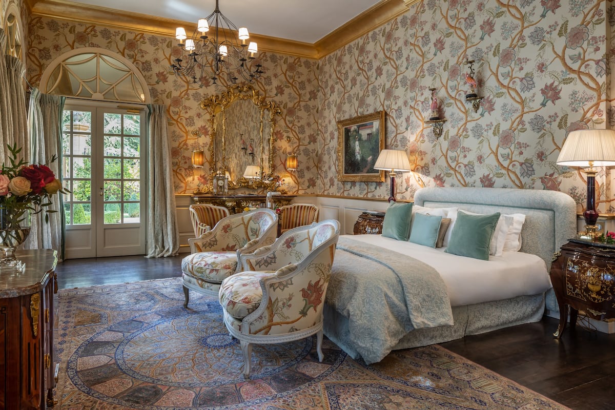Une chambre à coucher avec un grand lit, un papier peint à motifs floraux et un lustre.