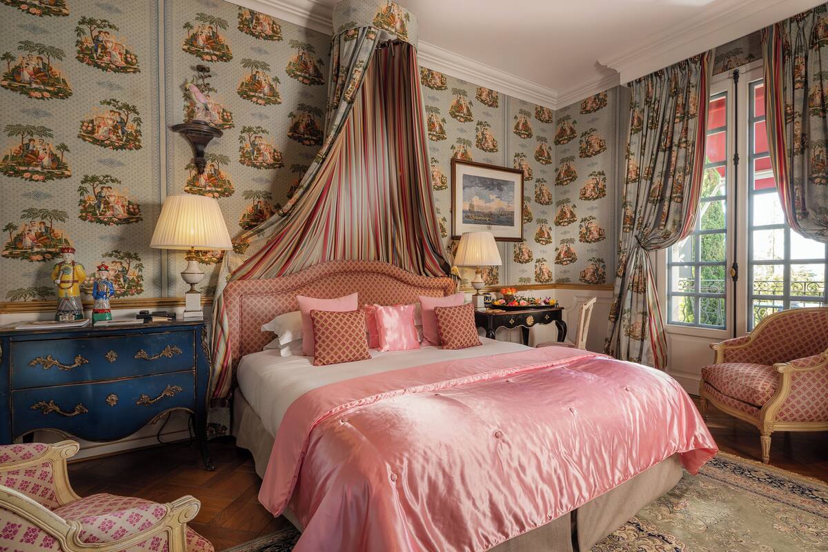 Une chambre à coucher avec un lit à baldaquin, un papier peint à motifs et des meubles classiques.