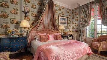 A bedroom with a canopy bed, patterned wallpaper, and classic furniture.