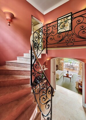 A staircase with ornate black metal railings leading to a room with a dining area visible through an open door.