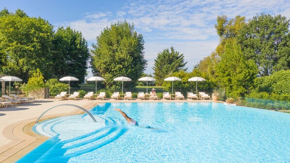 Una piscina al aire libre, cabañas de piscina (de pago), sombrillas