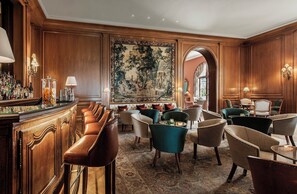 A bar area with leather chairs, a large painting, and wooden paneling.