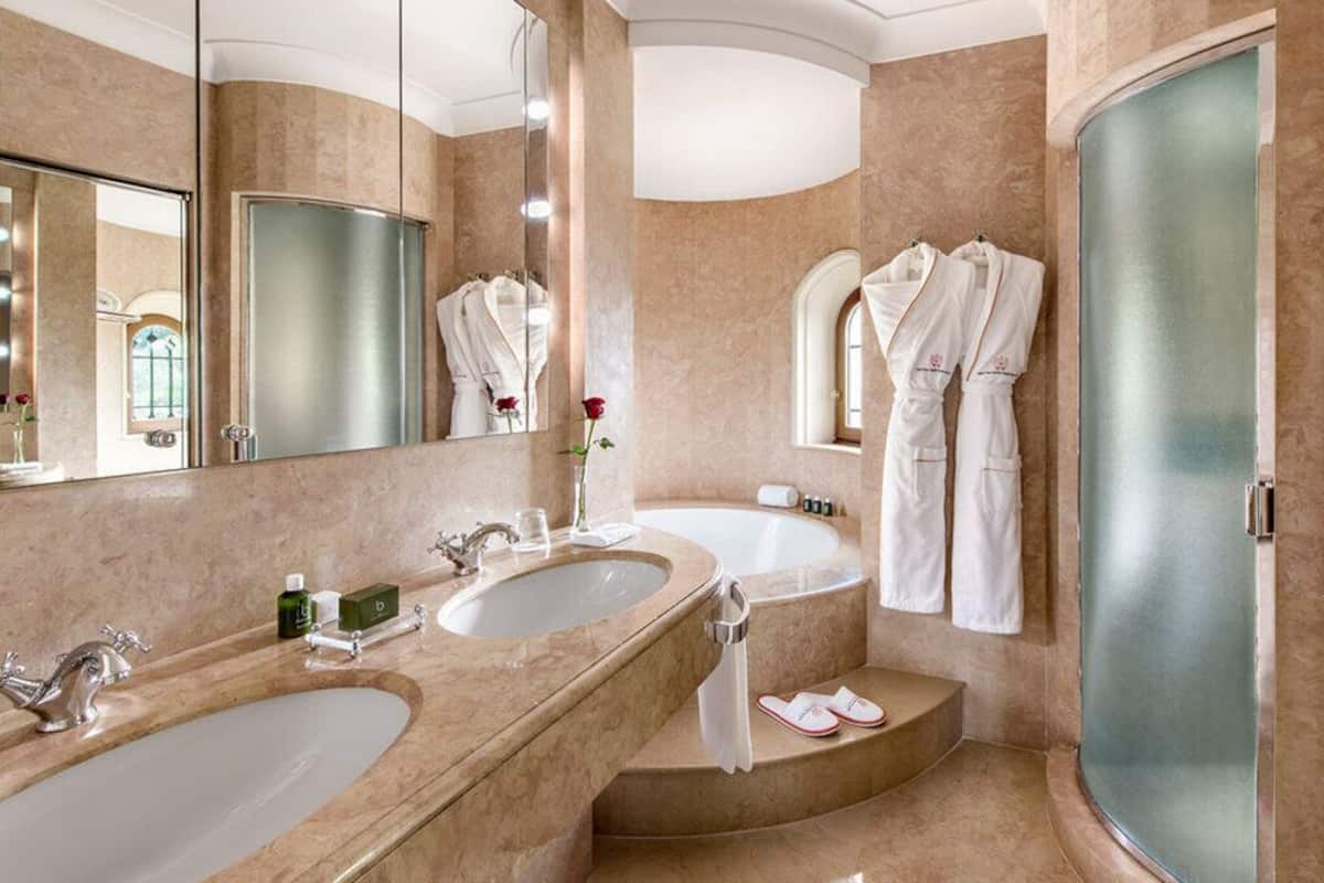 A bathroom with two sinks, a large mirror, and a shower.
