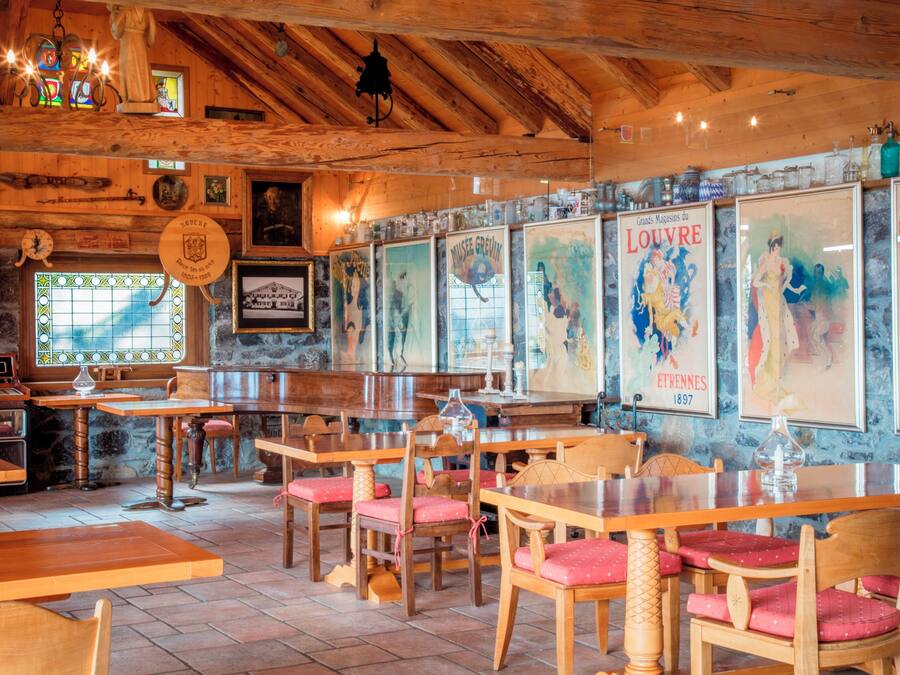 A restaurant interior with wooden tables and chairs, stained glass windows, and various framed artworks on the walls.