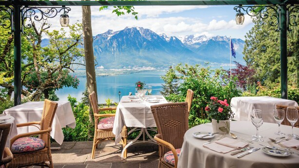 A terrace with tables set for dining, overlooking a mountainous landscape and a lake. - Hotel Victoria (Montreux)