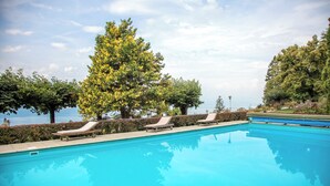 A swimming pool with lounge chairs and a large tree in the background. - Hotel Victoria (Montreux)