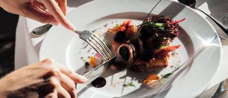 A dining table with a plate of food, utensils, and a glass of water.