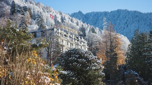 A building with a sign reading "VICTORIA" surrounded by snow-covered trees and a mountain in the background. - Hotel Victoria (Montreux)