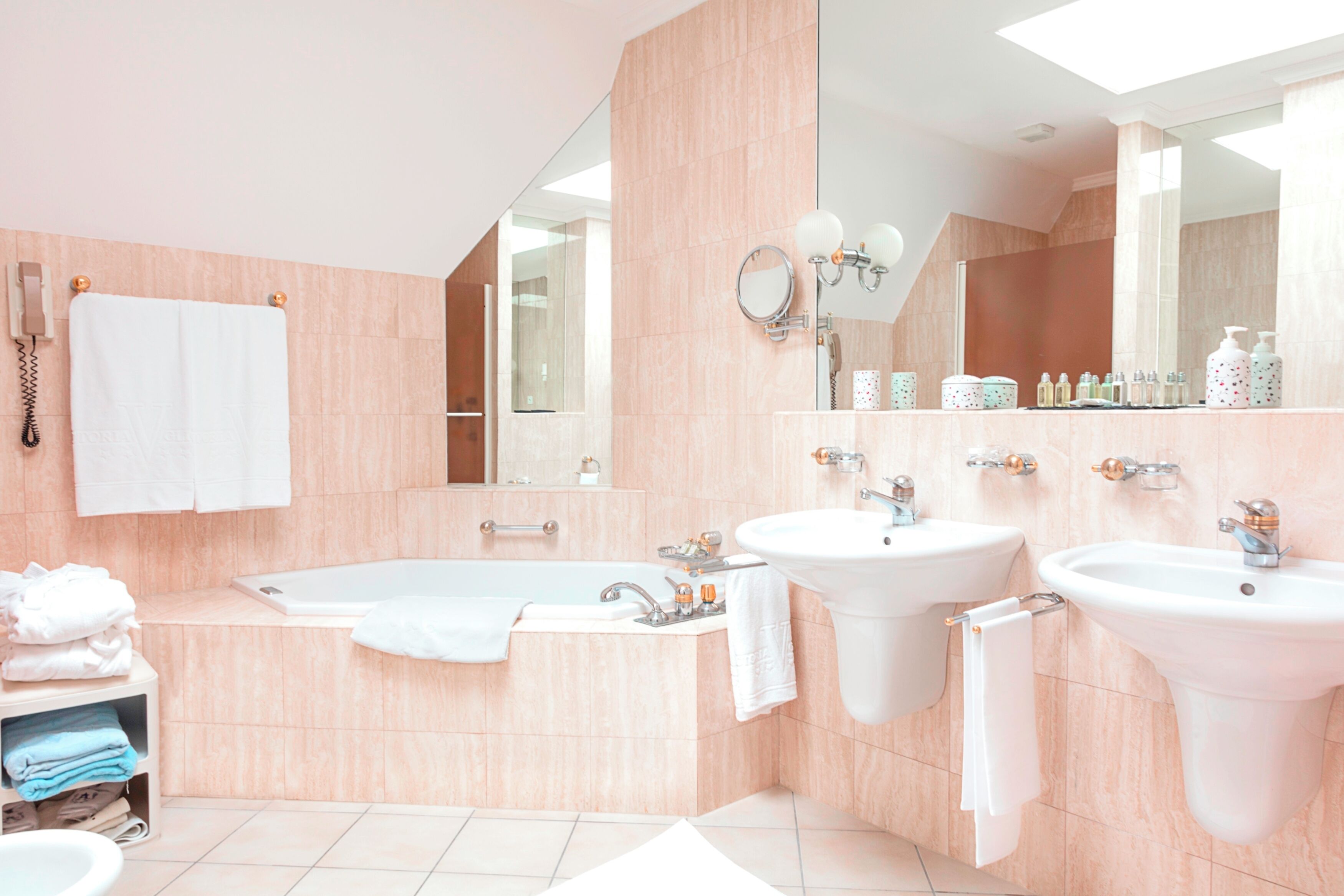 A modern bathroom with a bathtub, two sinks, and a large mirror.