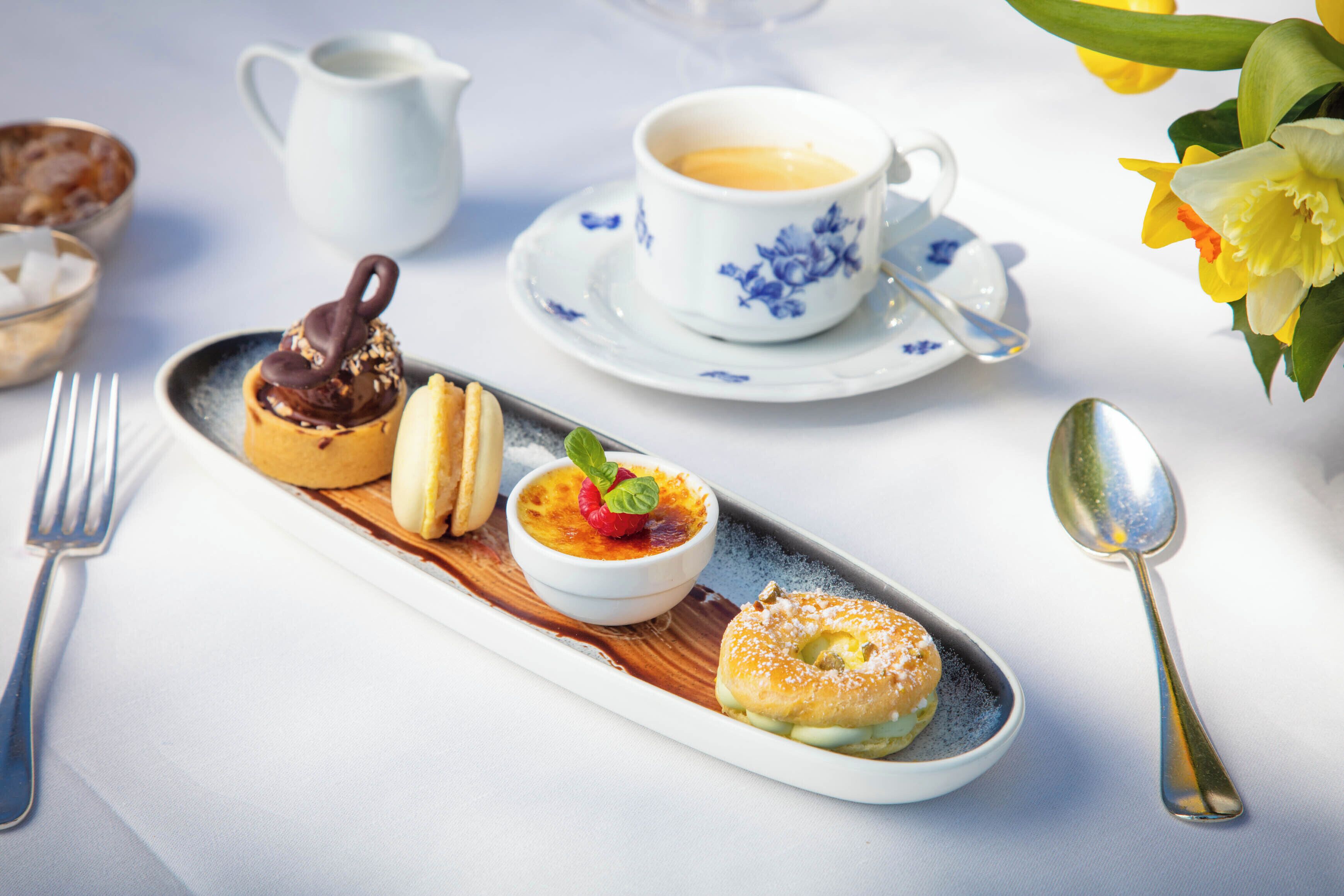 Een nagerechtenbord met een chocoladegedekte patisserie, een fruittaart en een suikerpoeder-donut.
