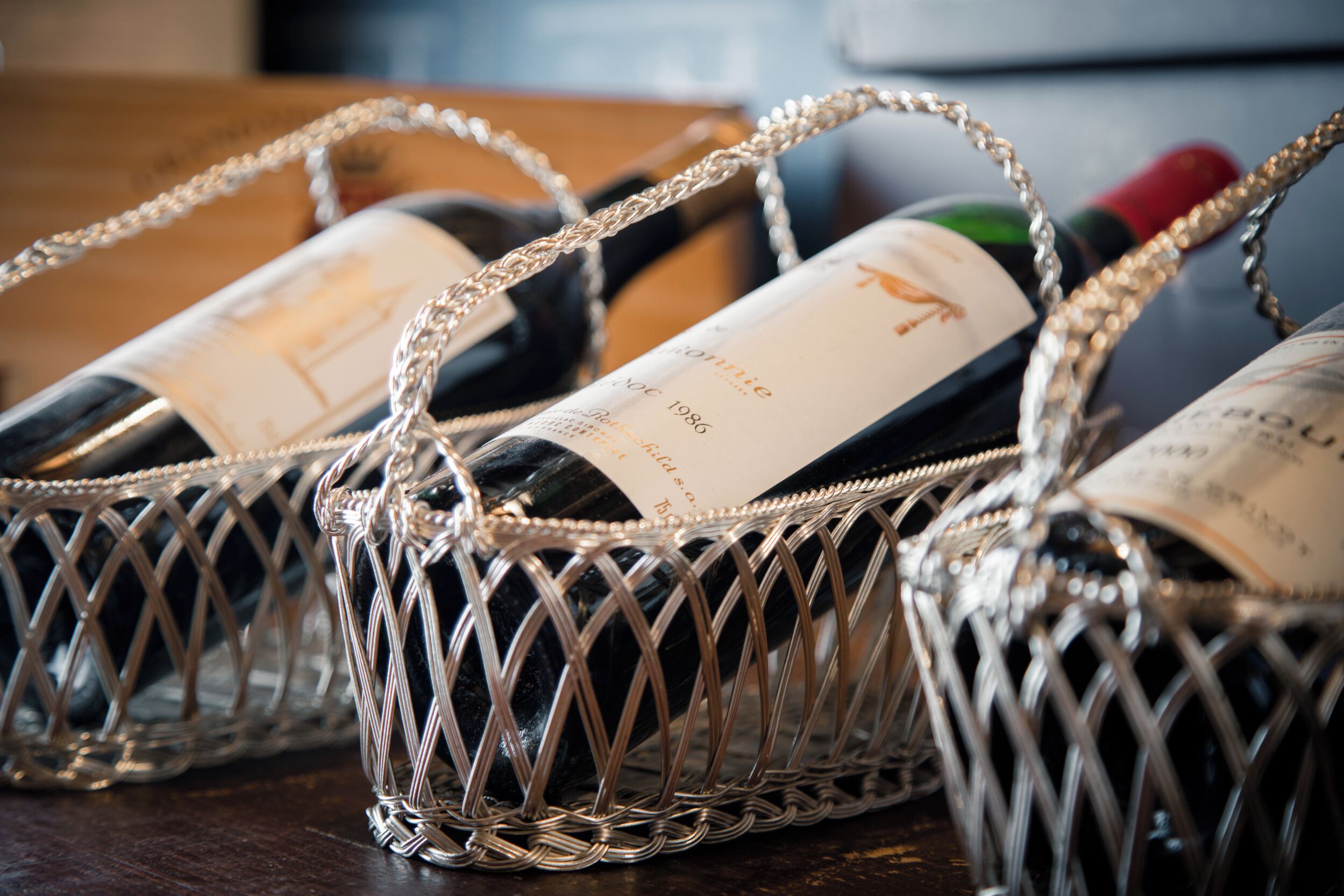 Three wine bottles in a decorative metal basket.