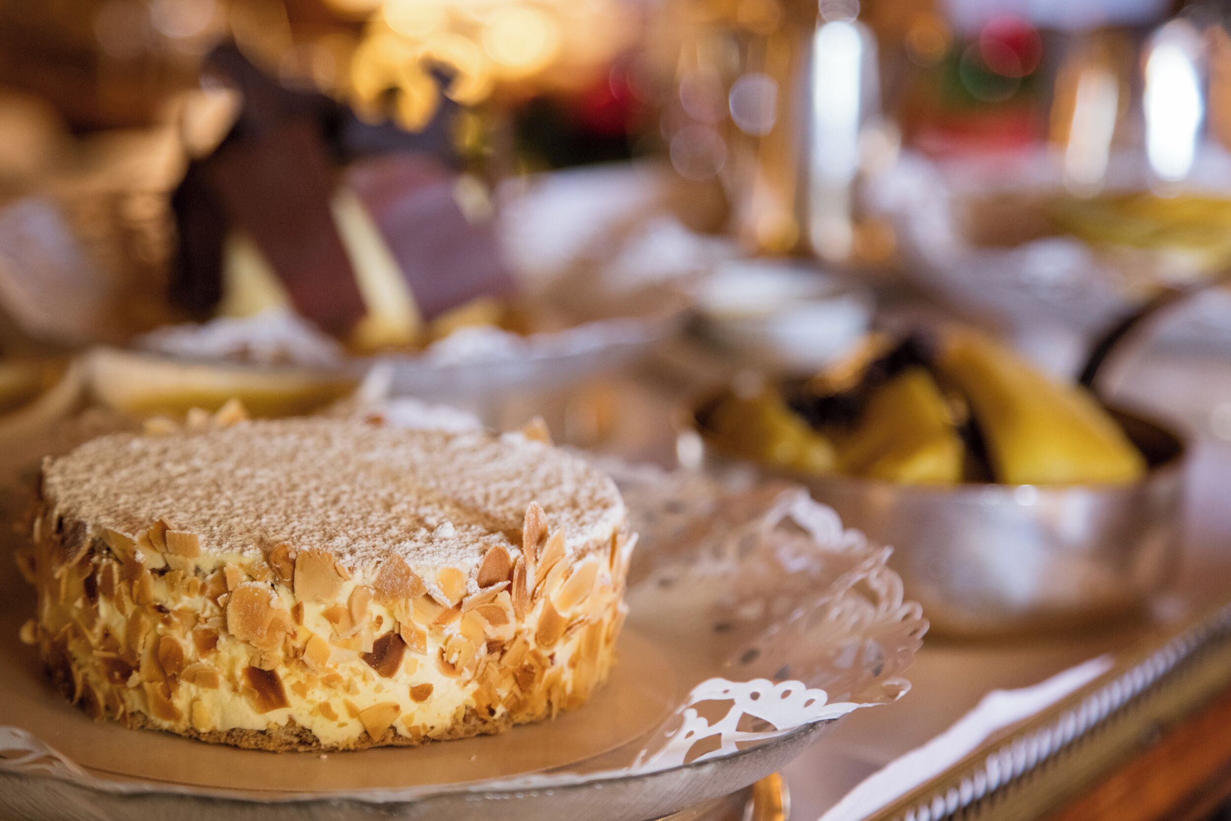 A dessert plate with a cake on a glass plate, accompanied by a bowl of fruit.