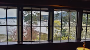 A view through a window with a view of a lake, boats, and trees. - Hastings House Country House Hotel (Salt Spring Island)