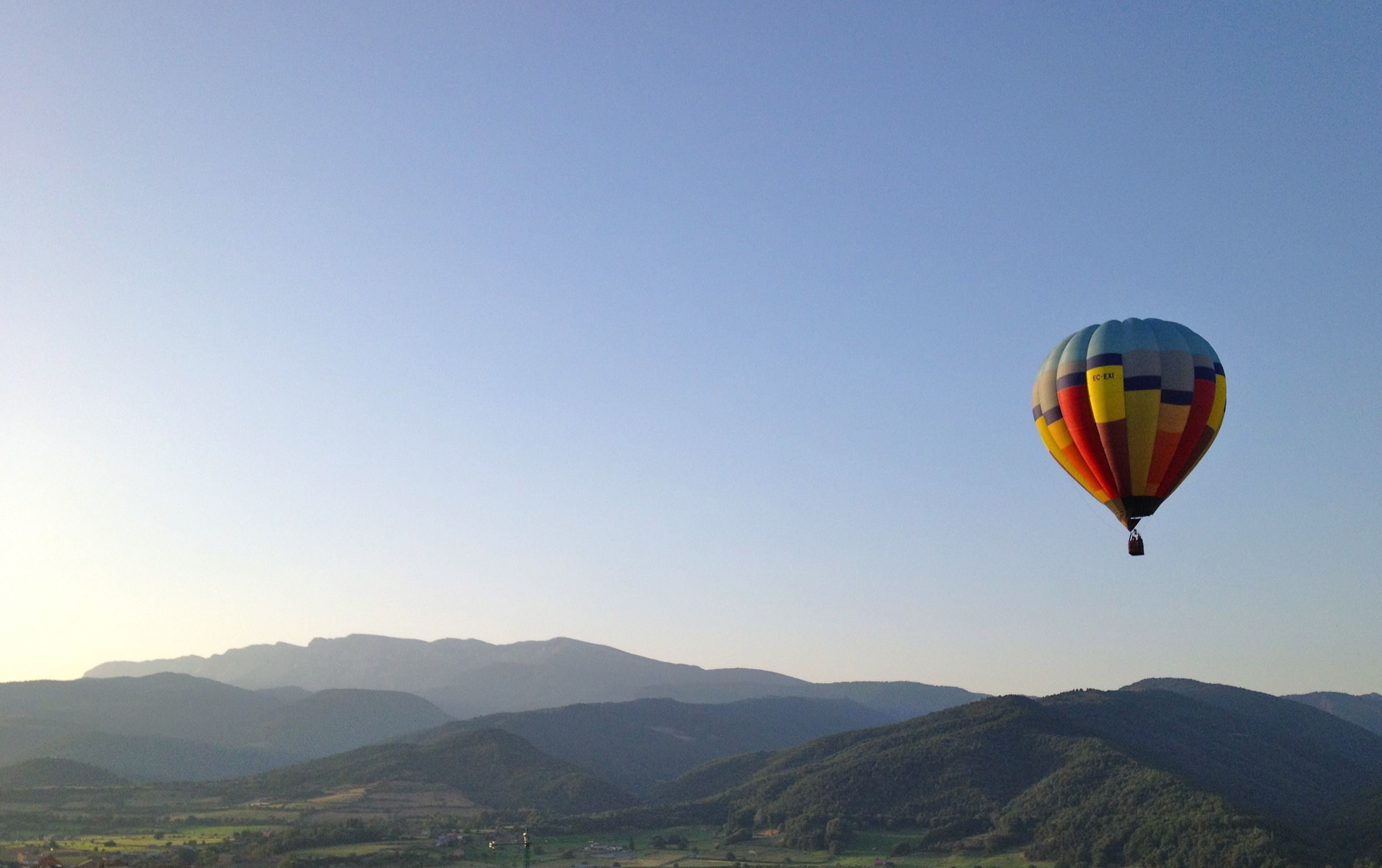 A hot air balloon flying over a mountainous landscape.