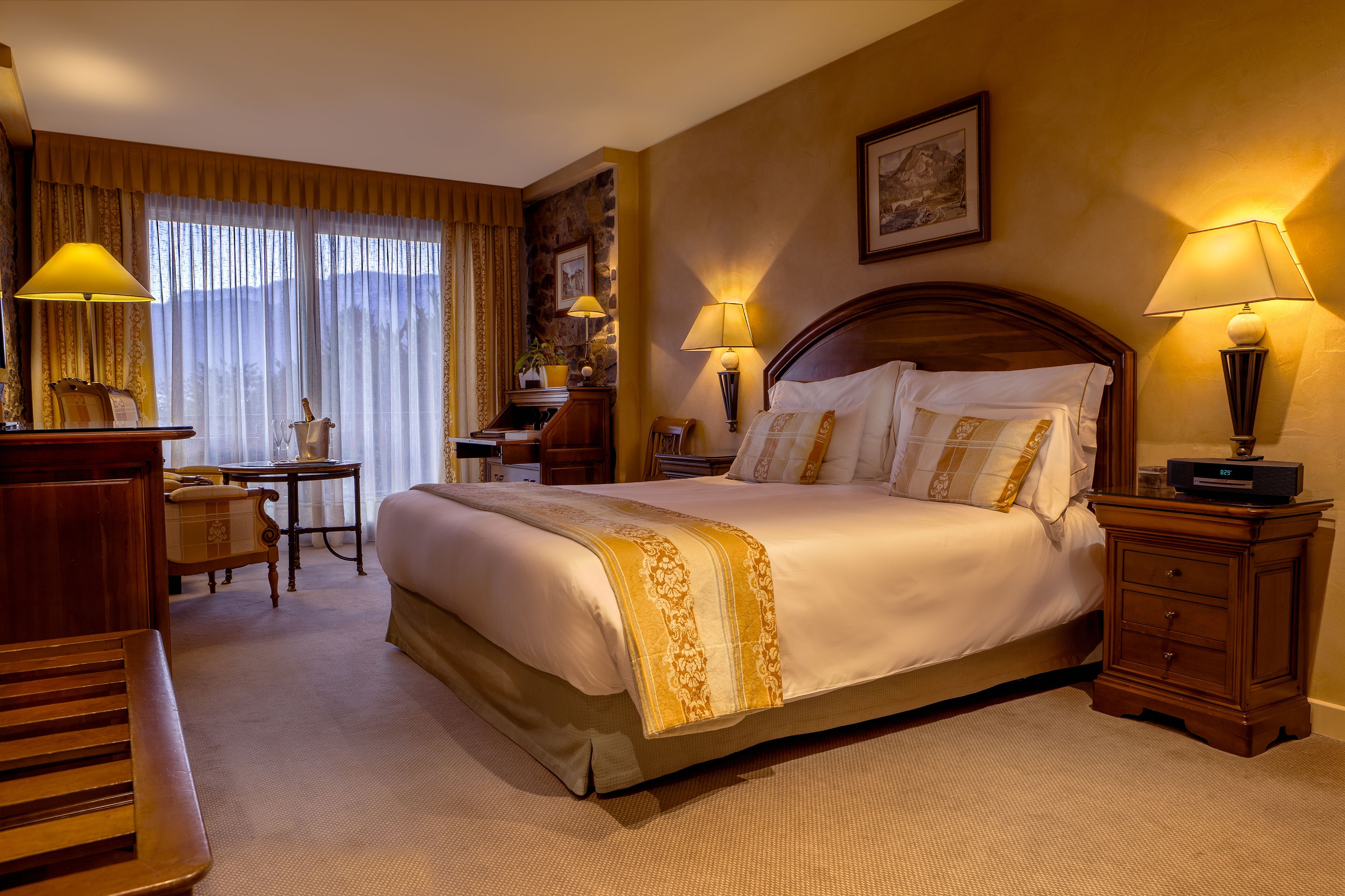 A hotel room with a large bed, bedside tables, a desk, and a chair.