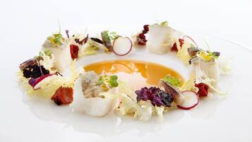 A white plate with a variety of food items including fish, vegetables, and a sauce.