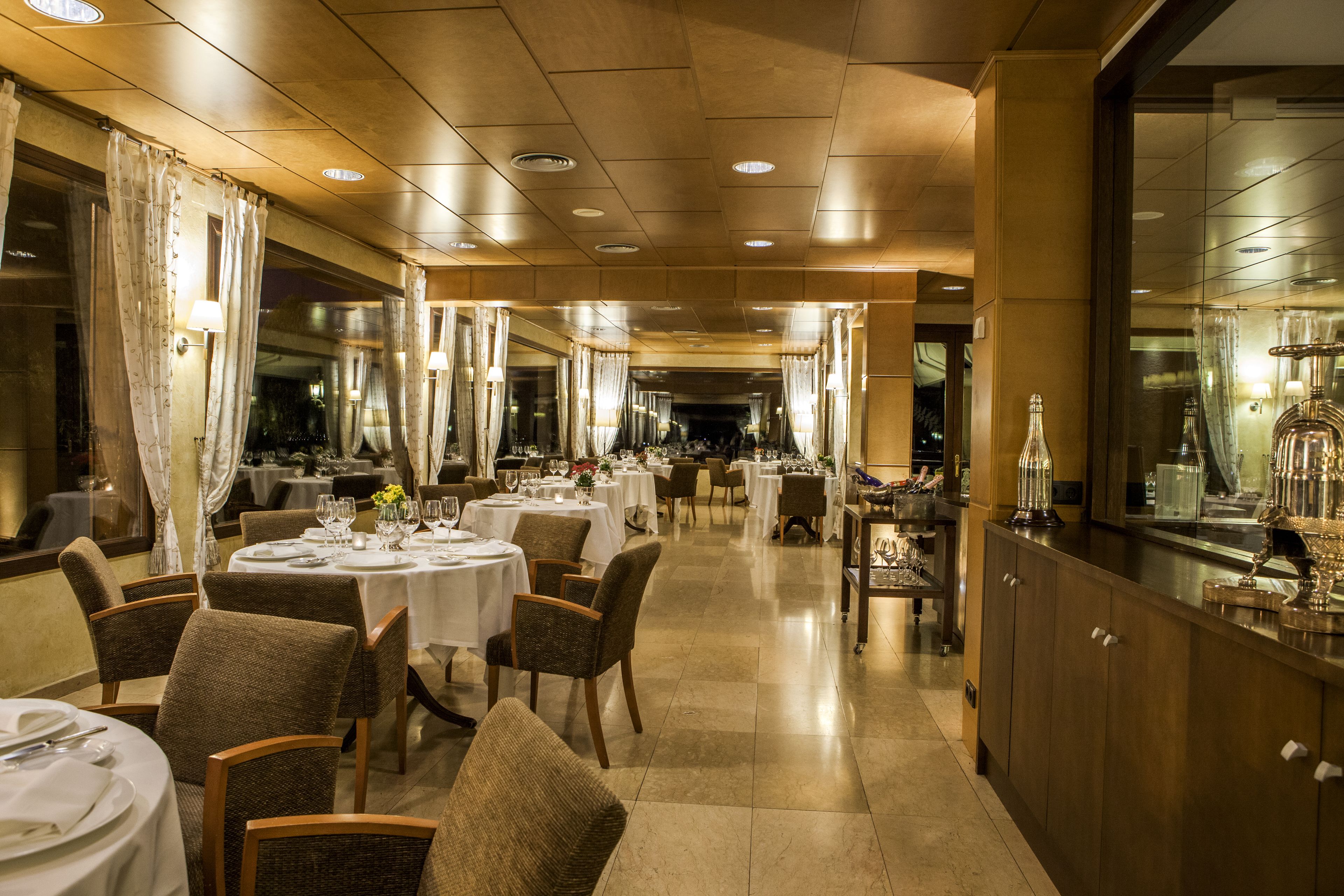 A spacious restaurant with multiple tables and chairs, a long counter, and a well-lit interior.