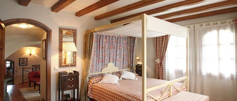 Un dormitorio con una cama con dosel, techo de madera y un espejo en la pared.