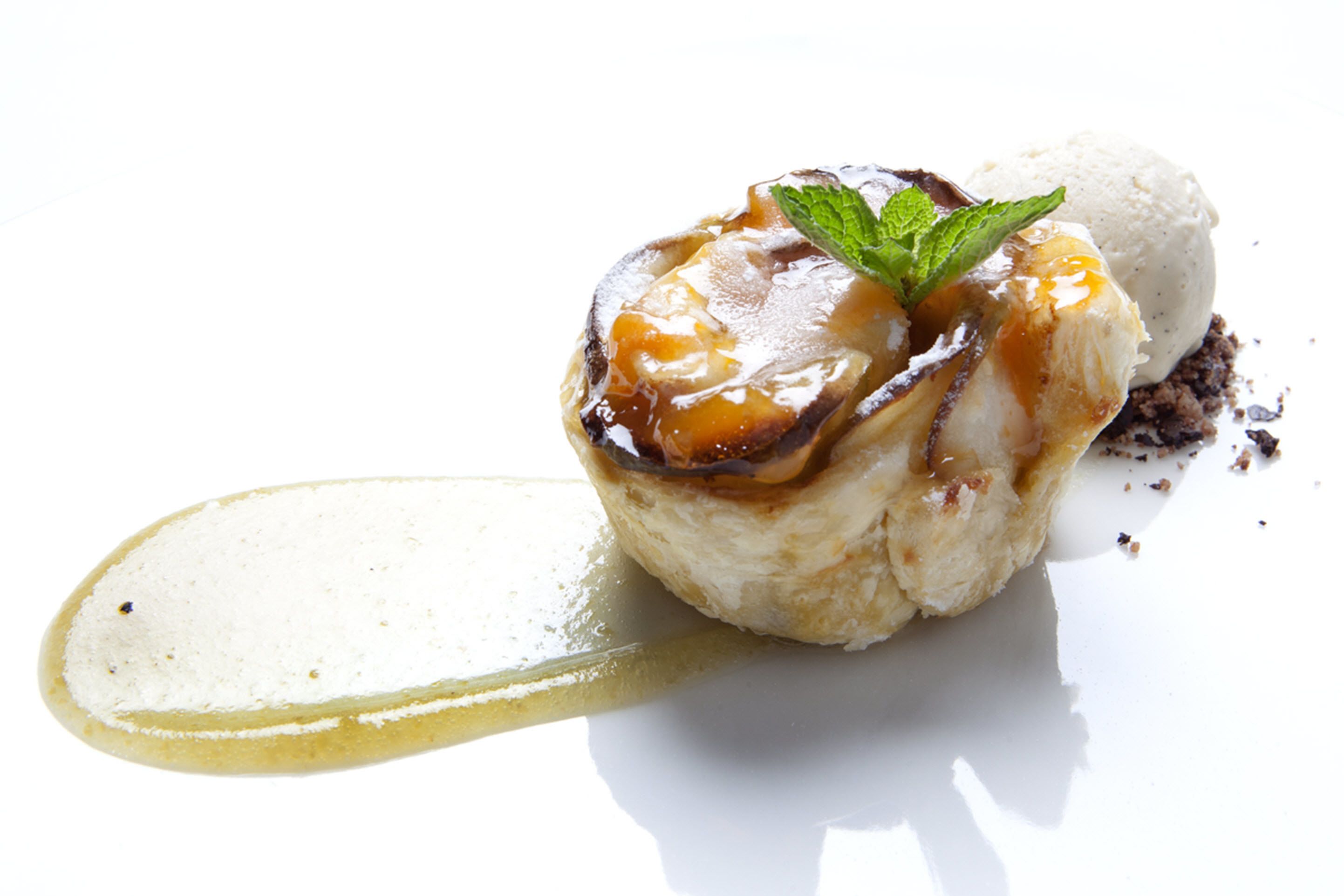 A dessert on a white plate with a caramelized top and a mint leaf garnish.