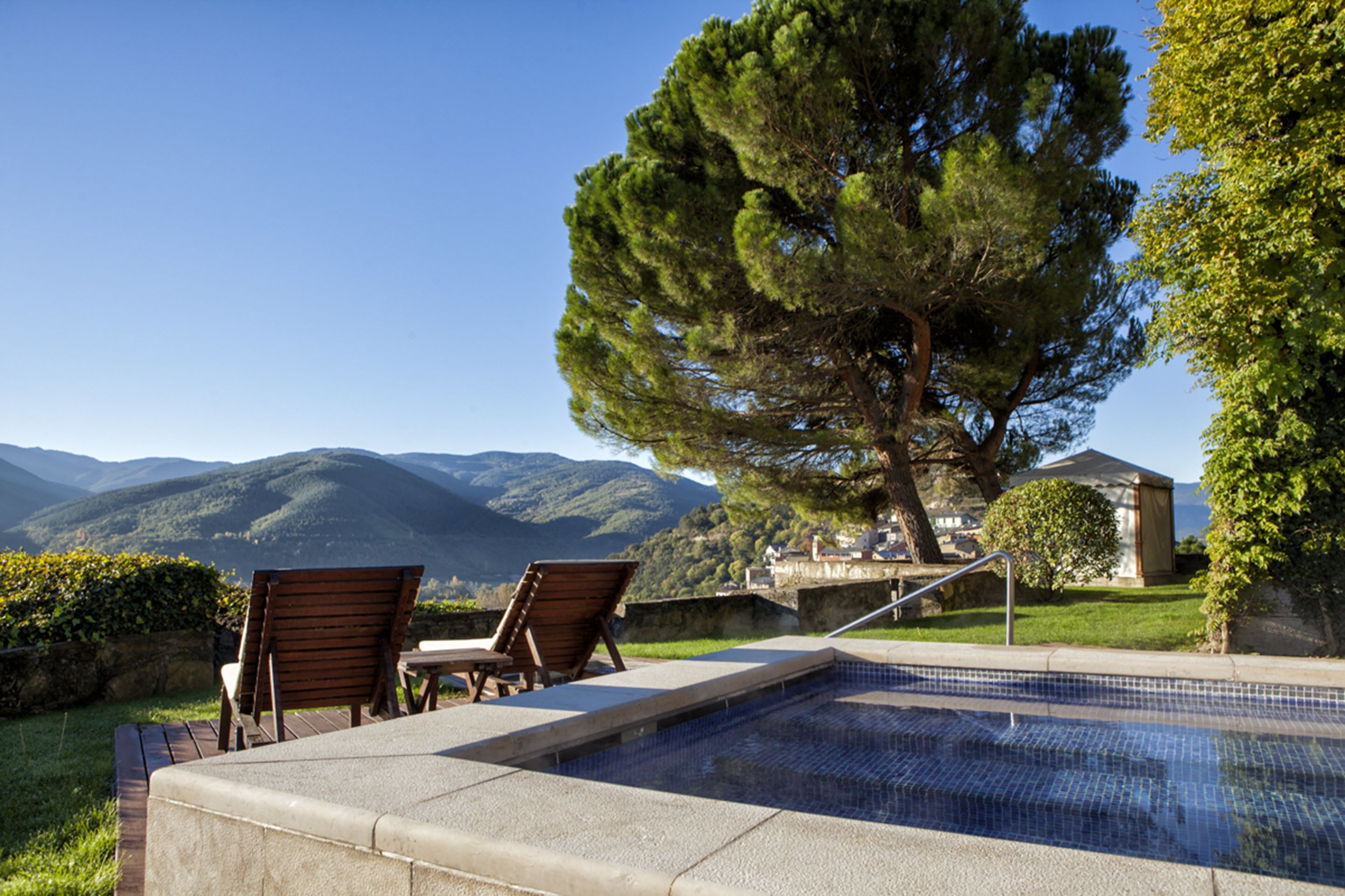 Zona de piscina con sillones de descanso y vistas a las montañas.