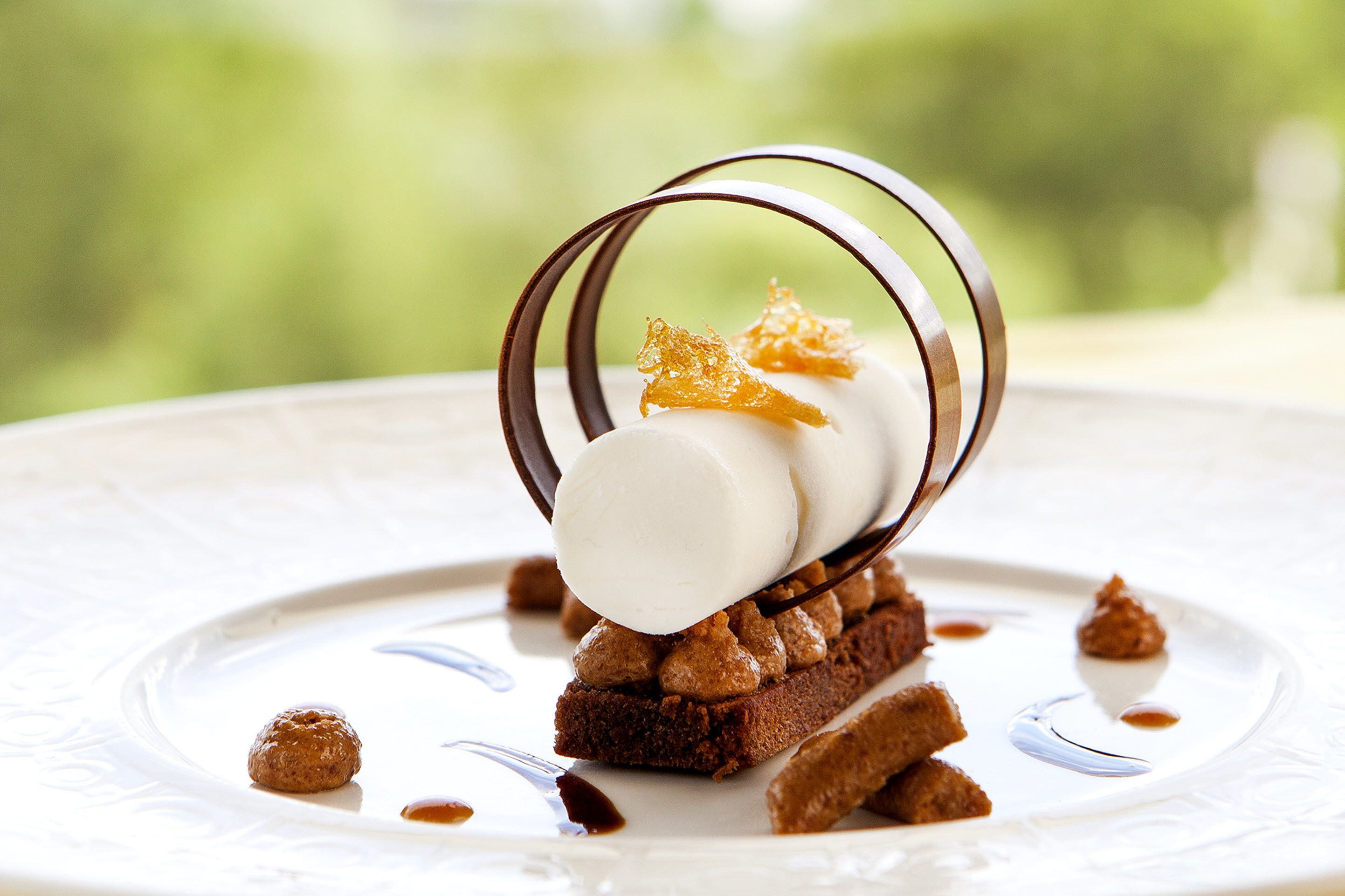 Postre con helado, caramelo y nueces en un plato.