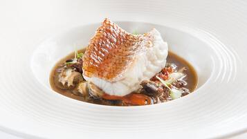 A white plate with a fish fillet, mushrooms, and a sauce.