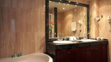 Un baño moderno con un espejo grande, dos lavamanos, una bañera y armarios de madera.