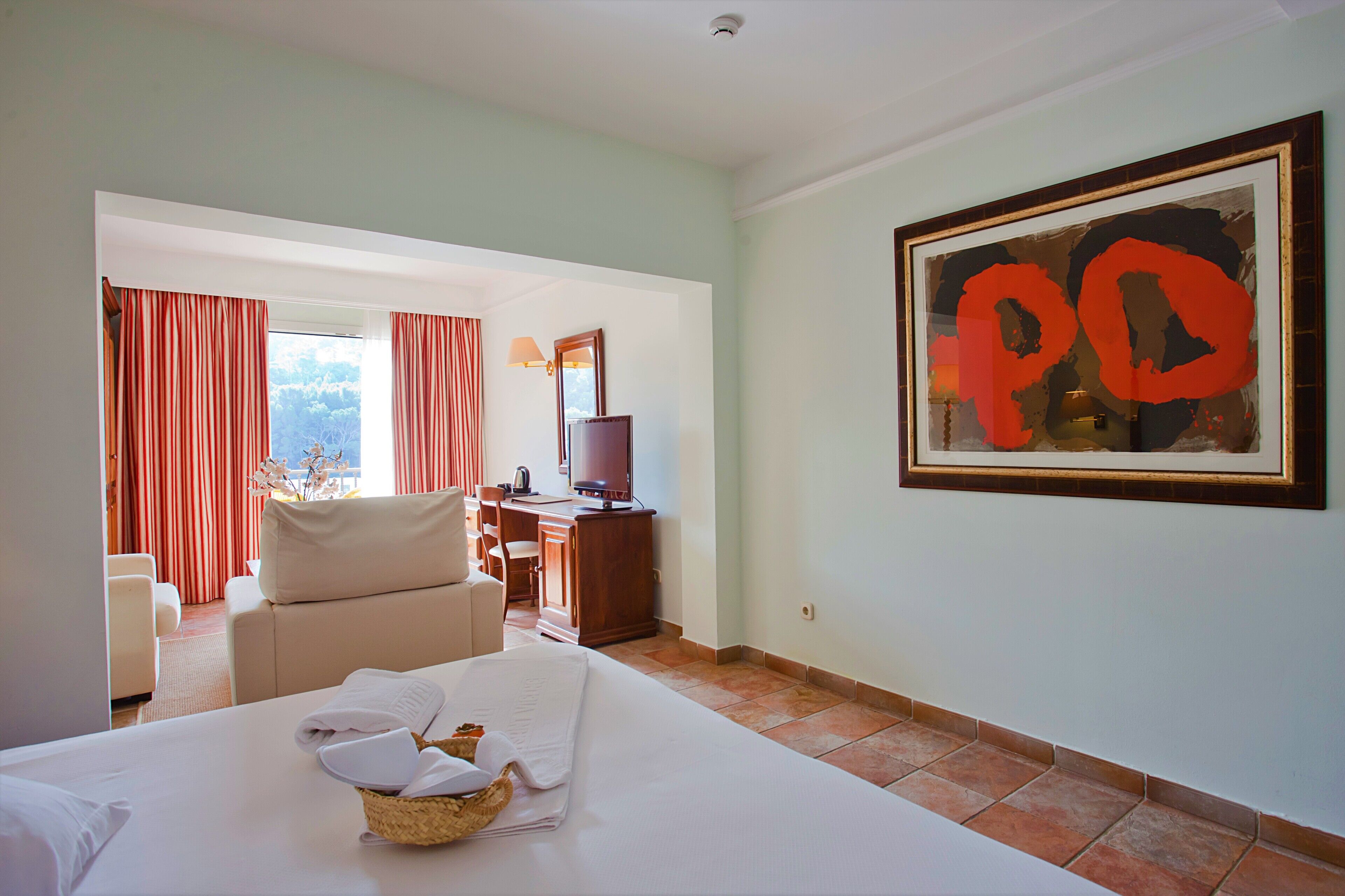 A hotel room with a bed, a desk, a chair, and a TV.