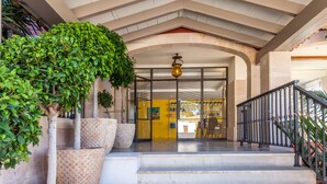 A hotel entrance with a modern design, featuring a staircase, a glass door, and a metal railing.