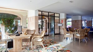 A spacious lobby with a reception desk, wicker chairs, and a patterned carpet.