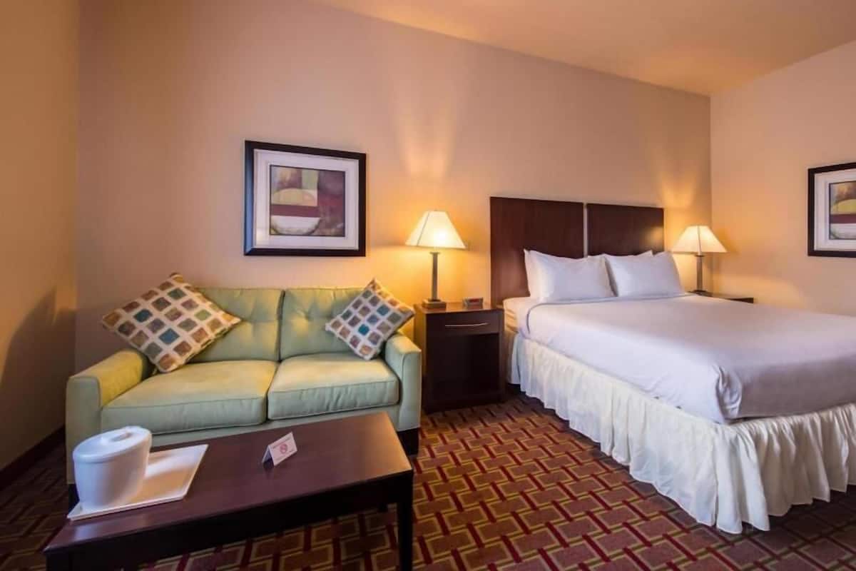 Una habitación de hotel con una cama, un sofá, una mesa y dos lámparas.