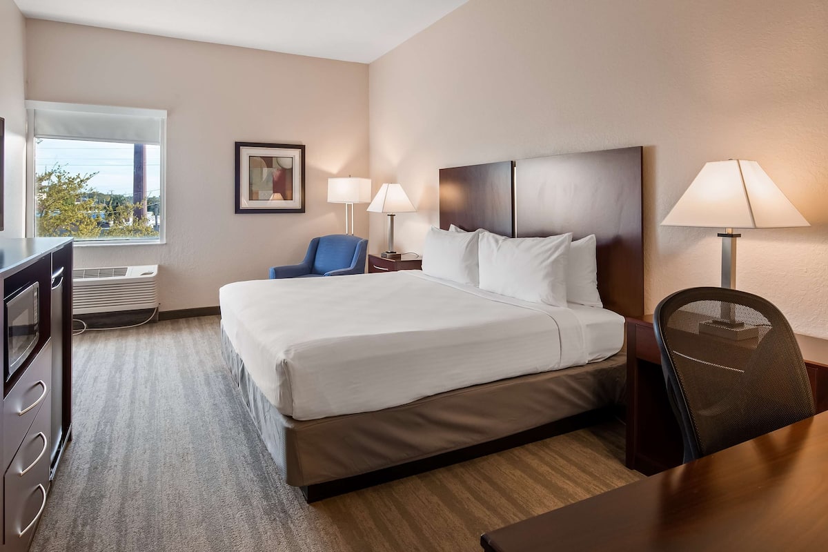 Una habitación de hotel con una cama, un escritorio, una silla, un televisor y una ventana.