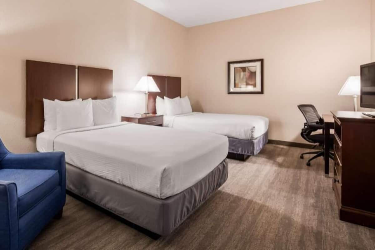 Una habitación de hotel con dos camas, un escritorio, una silla y un televisor.