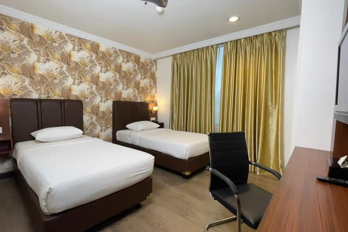 A hotel room with two beds, a desk, a chair, a TV, and a curtain.