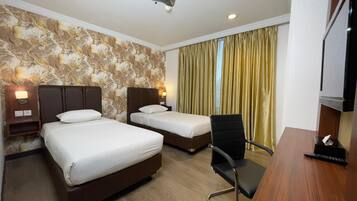 A hotel room with two beds, a desk, a chair, a TV, and a curtain.