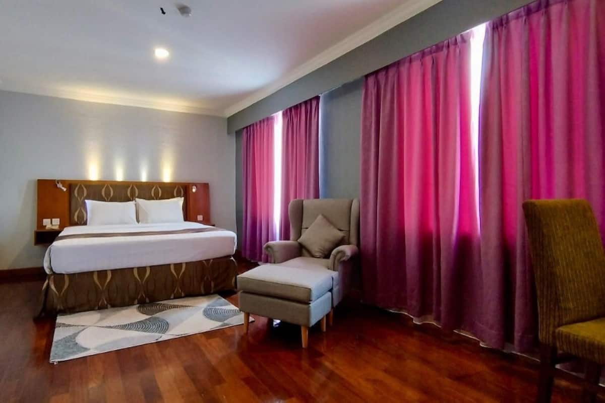 A hotel room with a bed, a chair, and a sofa.
