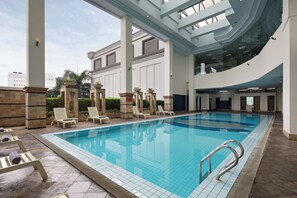 A large indoor swimming pool with lounge chairs and a modern architectural design. - Golden Boutique Hotel Kemayoran (Jakarta)