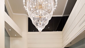 A spacious, well-lit atrium with a large, ornate chandelier, a circular floor pattern, and a modern interior design.