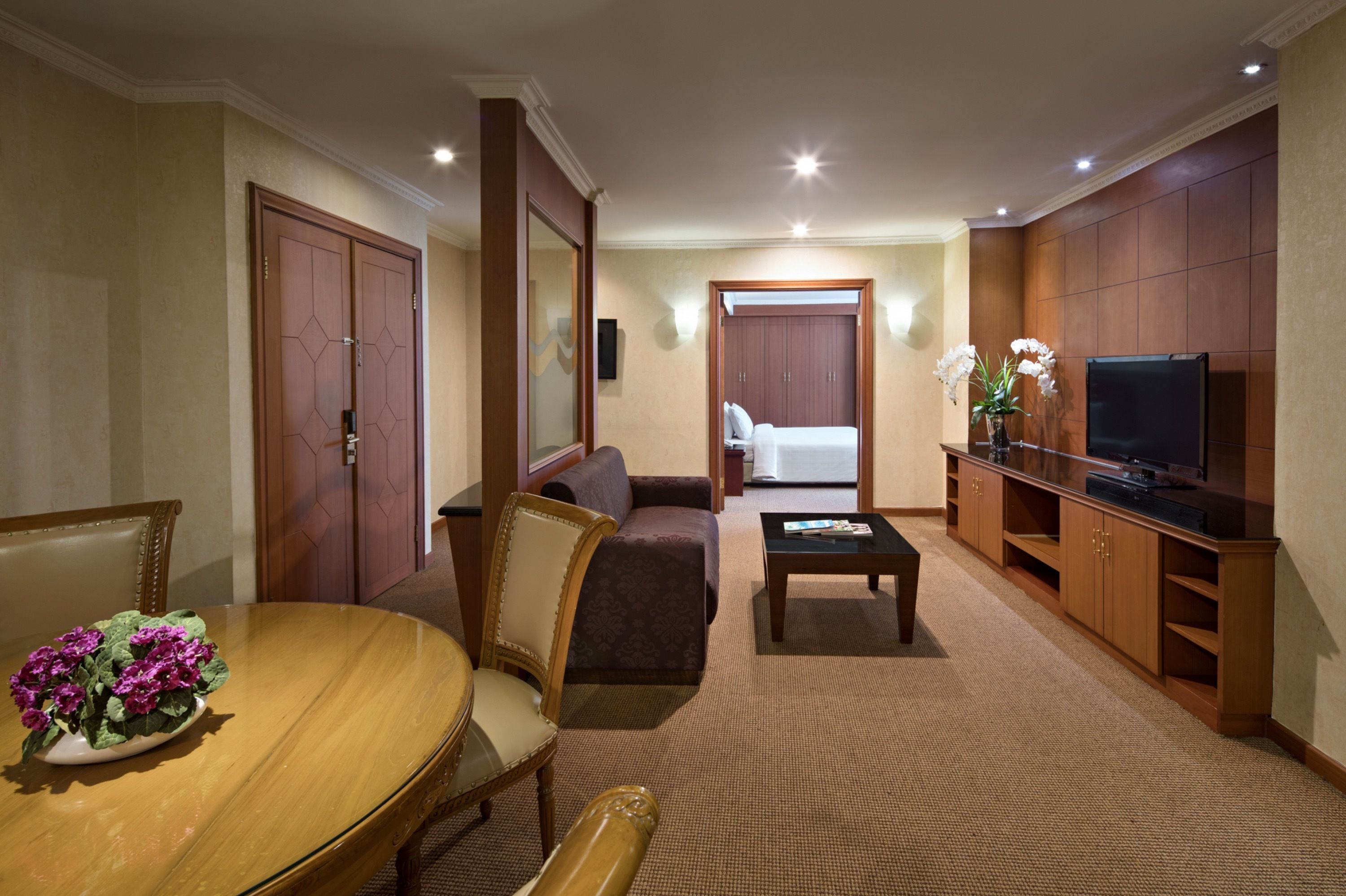 Ein Hotelzimmer mit Esstisch, Stühlen, einer Couch, einem Fernseher und einem Schrank.