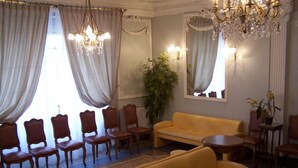 A room with a yellow sofa, wooden chairs, a round table, and a chandelier. - Hotel Gloria et Avenue (Lourdes)
