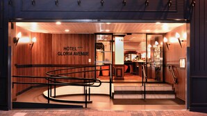 A hotel entrance with a wooden facade, a sign reading "HOTEL GLORIA AVENUE", and a staircase leading inside. - Hotel Gloria et Avenue (Lourdes)